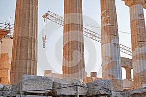 Machine crane between columns of Parthenon temple at the Acropolis, Athens, Greece, at sunset. Restoration process