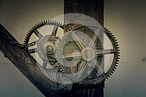 The machine gear of engaging old rusty metal industrial cogwheels installed on wooden structure at a farmhouse