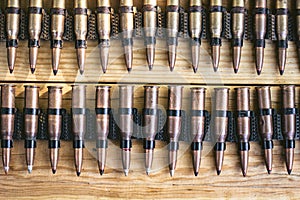 Machine gun ammo on a wooden table, bullet belt, bandoleer, chain of ammo on wooden background,cartridge 7.62 mm caliber, top view