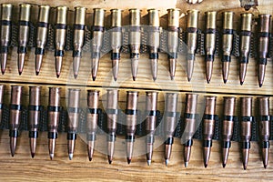 Machine gun ammo on a wooden table, bullet belt, bandoleer, chain of ammo on wooden background,cartridge 7.62 mm caliber, top view