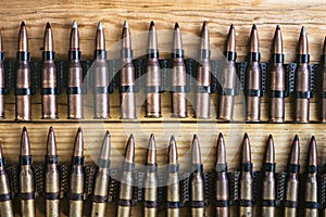 Machine gun ammo on a wooden table, bullet belt, bandoleer, chain of ammo on wooden background,cartridge 7.62 mm caliber, top view