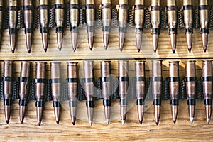 Machine gun ammo on a wooden table, bullet belt, bandoleer, chain of ammo on wooden background,cartridge 7.62 mm caliber, top view