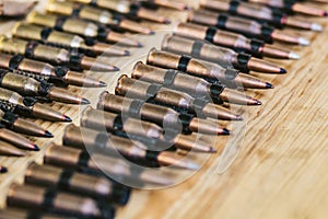 Machine gun ammo on a wooden table, bullet belt, bandoleer, chain of ammo on wooden background,cartridge 7.62 mm caliber