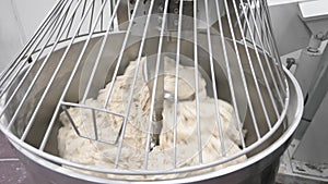 Machine kneading bread dough. Raw dough in a industrial bakery dough mixer, food concept.