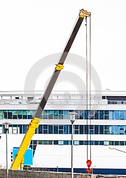 Machine lifting crane industrial equipment at a construction site on the background of a new, modern facade of an urban building