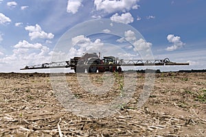 Machine for spraying pesticides and herbicides in the field against blue sky. Heavy machinery for agriculture photo