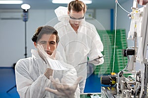 Machine staff, mask production department. Engineer wearing protective suit Inspecting quality of masks. machine production