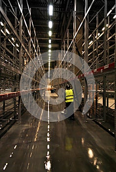 Worker scrubbing floor in empty warehouse