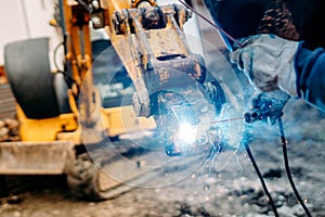 Machinery being repaired on construction site. mechanic welder working on excavator