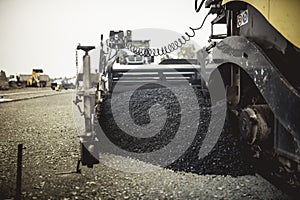 Machinery laying fresh asphalt or bitumen during road construction on building site. vintage, retro effect on photo