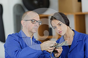 Machinery repairman and female apprentice processing metal piece