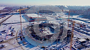 Machines and laborers build new sports arena on winter day