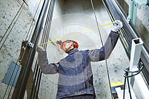 Machinist with measure tape checking lift construction in elevator shaft