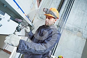 Machinist with spanner adjusting lift mechanism in elevator shaft