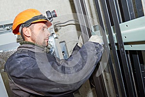 Machinist with spanner adjusting lift mechanism in elevator shaft