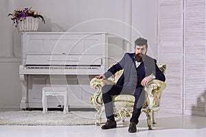 Macho attractive and elegant on serious, thoughtful face sitting on old fashioned armchair. Wealth and richness concept