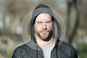 Macho with beard in hood on sunny day. Bearded man wear casual sweatshirt outdoor. Fashion guy in stylish sportswear. Lifestyle fo