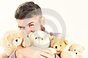 Macho with beard hugs many teddy bears and plush toys. photo