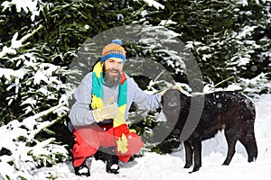 Macho with beard pats black dog. Winter walks concept. photo
