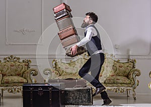 Macho elegant accidentally stumbled, dropping pile of vintage suitcases. Butler and service concept. Man with beard and