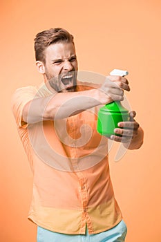 Macho hold plastic spray bottle as gun yellow background. Guy with water spray in hand pretend shooting attack