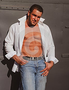 Macho man bristle. Sexy male stylish body. Brutal guy in white shirt on gray background.