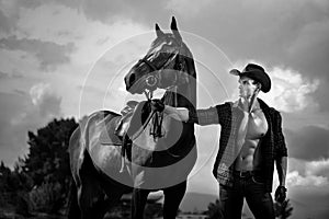 Macho man handsome cowboy and horse on the background of sky and water. photo