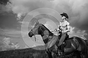 Macho man handsome cowboy and horse on the background of sky and water. photo