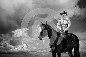 Macho man handsome cowboy and horse on the background of sky and water. photo