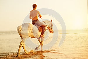 Macho man and horse on the background of sky and water. Boy mode photo