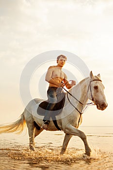 Macho man and horse on the background of sky and water. Boy mode photo