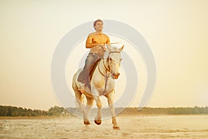 Macho man and horse on the background of sky and water. Boy mode photo