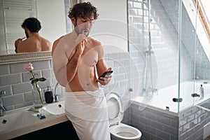 Macho topless man texting while brushing teeth