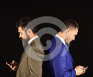Machos in classic suits text on mobile phone. photo