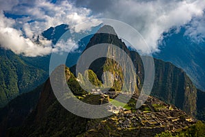 Machu Picchu illuminated by the first sunlight coming out from the opening clouds. The Inca`s city is the most visited travel des