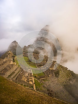 Machu Picchu illuminated by the first sunlight coming out from the opening clouds. The Inca`s city is the most visited travel des