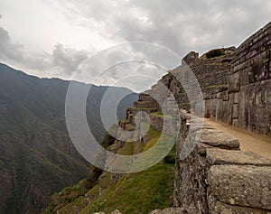 Machu Picchu Terraces and inca stone wall mountain range and clouds in the background