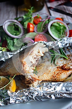 Mackerel baked in foil with vegetables on a plate.