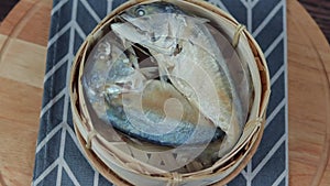 Mackerel fish in a bamboo basket rotating on a wooden plate