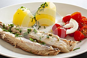 Mackerel fish dish with potatoes, chives and tomato salad. Fatty, oily fish is an excellent and healthy source of DHA and EPA, whi