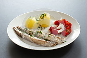 Mackerel fish dish with potatoes, chives and tomato salad. Fatty, oily fish is an excellent and healthy source of DHA and EPA, whi