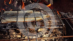 Mackerel fish fillet is flipped on the grill grid over the flames