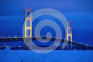 Mackinac Bridge at Night in Winter. Blue ice stacks in the Straits of Mackinac are shown in the foreground