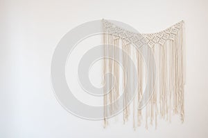 A macrame hanging on white cement wall for home and wedding decoration with copy space