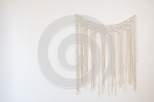 A macrame hanging on white cement wall for home and wedding decoration with copy space photo