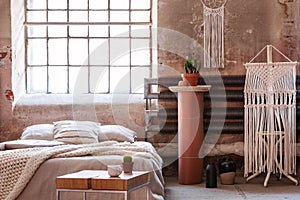 Macrame in a wabi sabi bedroom interior with a bed, table and stand with a plant