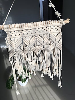 A macrame wall hanging decoration with an hourglass design in it.