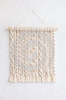 Macrame wallhanging with wooden beads. Wall panel of cotton threads in natural color. Macrame technique for eco home decor and