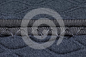 Macro background made of a seam on a fabric in navy blue color, rhomboid shapes.
