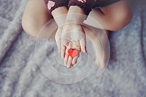 Macro of child with adult parent hands palms holding a bunch of small red and purple paper foam hearts